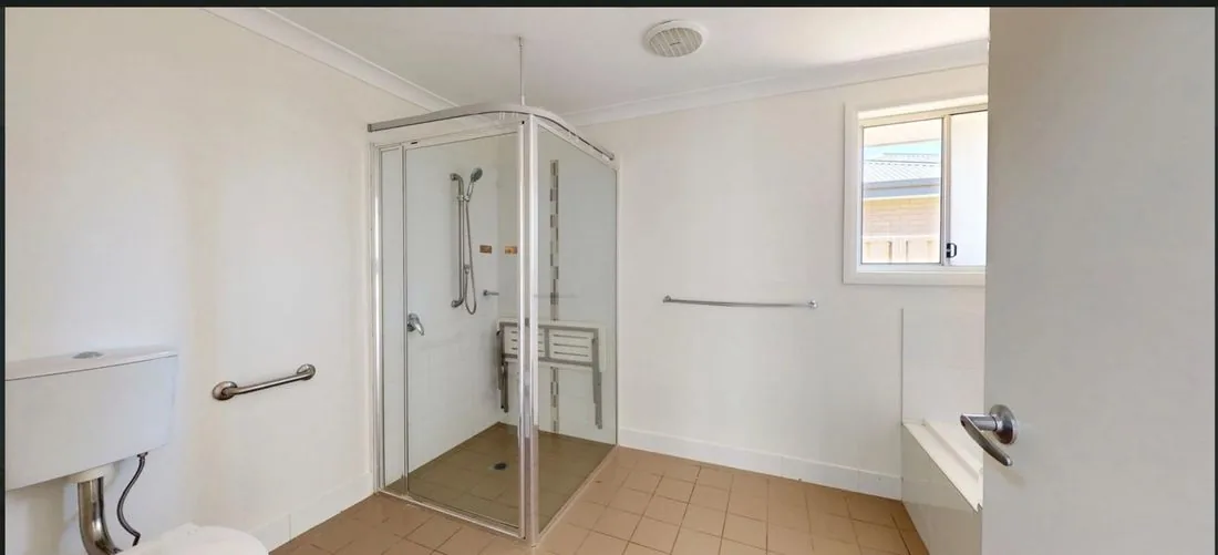 Accessible bathroom in one of our SIL homes with a step-free roll-in shower, fold-down shower seat, grab rails and support handles.